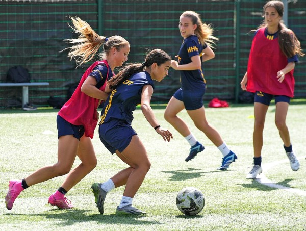 Jugadoras del campus femenino compitiendo por el balón durante un entrenamiento en Barcelona